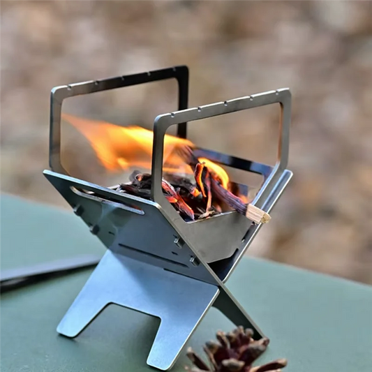 Portable metal stove with flames on a blurred natural background